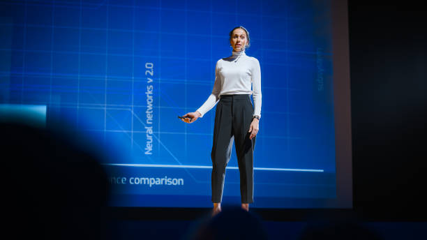 istock On-Stage Successful Female Speaker Presents Technological Product, Uses Remote Control for Presentation, Showing Infographics, Statistics Animation on Big Screen. Live Event / Business Conference 1226991467