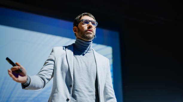 istock On-Stage Successful Male Speaker Presents Technological Product, Uses Remote Control for Presentation, Showing Infographics, Statistics Animation on Big Screen. Live Event / Business Conference 1226991592