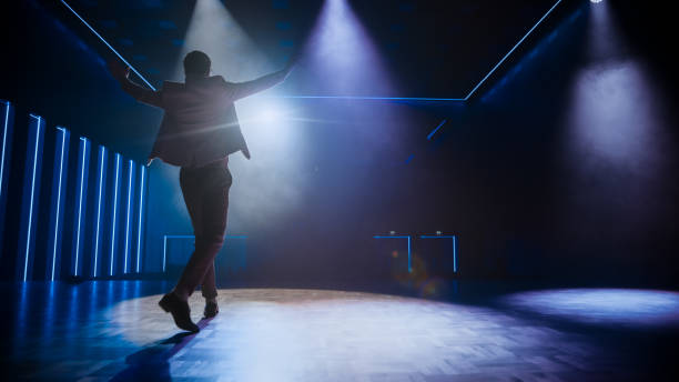 istock Famous Entertainer Gets on the Stage, Greets Audience, Starts Performance. Software Company Founder, Tech Marketing Guru Making a Pitch, Presentation Speaker Giving Talk. Cinematographic Back View 1226991612