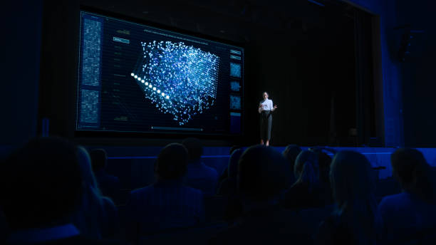istock Computer Science Startup Conference: On Stage Speaker Does Presentation of New Product, Talks about Neural Networks, Shows New AI, Big Data and Machine Learning App on Big Screen. Live Event 1226991693