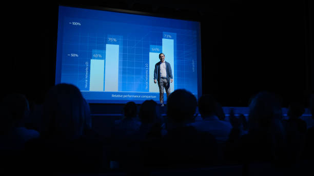 istock Startup Conference Stage: Speaker Presents New Product, Talks about Performance, Neural Networks, Artificial Intelligence, Big Data and Machine Learning. Live Business Event with Large Audience 1226991743