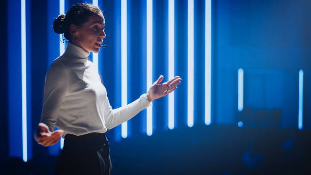 female motivational speaker on stage, talking about happiness, diversity, success, leadership, stem and how to be productive. woman presenter leads tech business conference. low angle portrait - set goals imagens e fotografias de stock