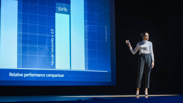 tech conference stage: visionary female speaker talks about product. neural networks, artificial intelligence, big data and machine learning. infographics on big screen. live startup business event - set goals imagens e fotografias de stock