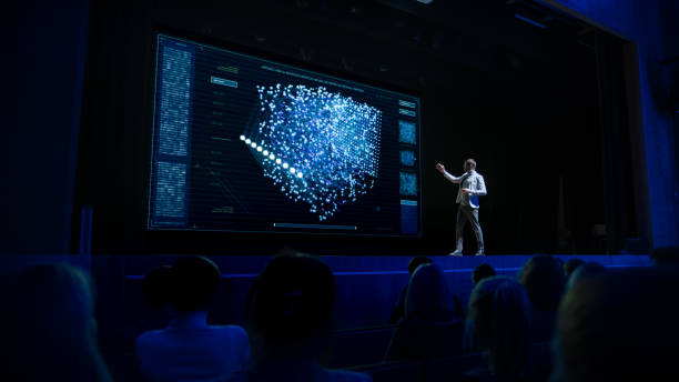 istock Computer Science Startup Conference: On Stage Speaker Does Presentation of New Product, Talks about Neural Networks, Shows New AI, Big Data and Machine Learning App on Big Screen. Live Event 1226992697