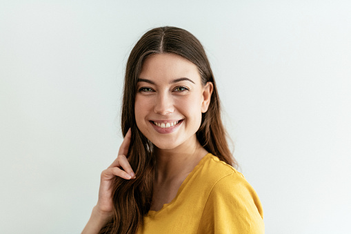 Mujer joven feliz con el pelo largo en camiseta amarilla photo