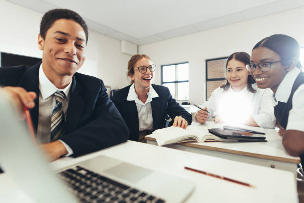 group of student studying together on a laptop in classroom - adult student college student school uniform student imagens e fotografias de stock