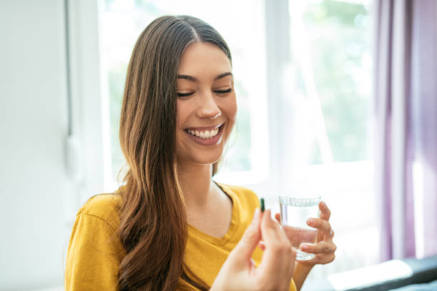 istock Healthy young woman taking pill and drinking water 1226994250