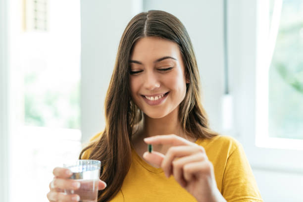 Healthy young woman taking herbal supplements and smiling