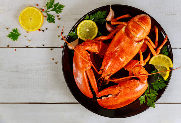 Boiled lobster in a black plate with lemon and parsley. Boiled red lobster in a black plate with lemon and parsley. tail fin photos stock pictures, royalty-free photos & images