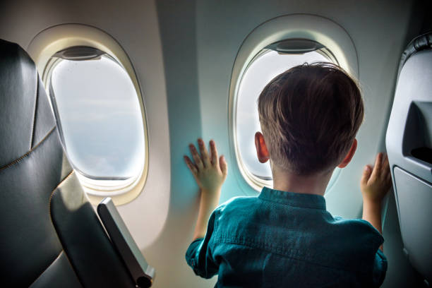 istock A boy have flight looking in the airplane window or porthole 1226995628