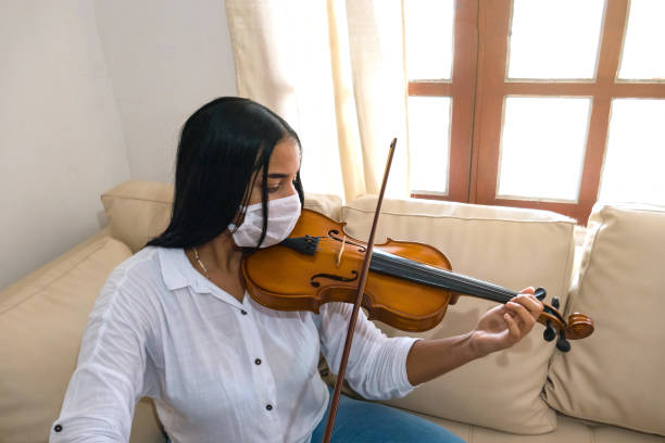 istock Woman with face mask practices violin at home 1226999315