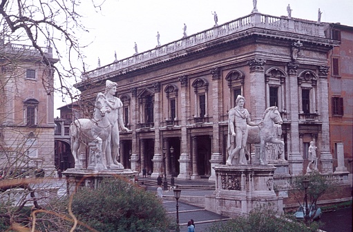 Rome, Latio, Italy, 1975. Statues of Castor and Pollux on the Capitol, in the background the Capitoline Museums. Also: Locals and visitors.