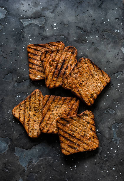 Whole grain seeds grilled toast bread for sandwiches on a dark background, top view