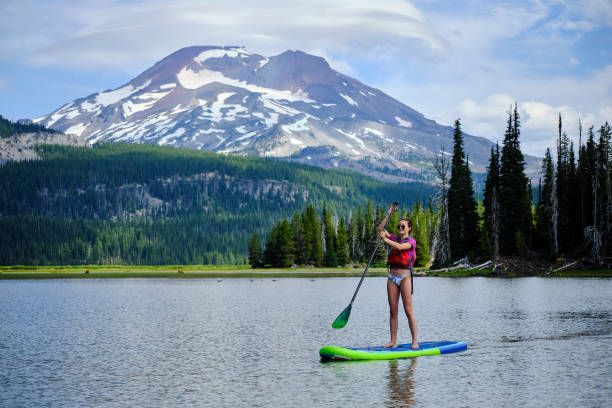 istock Young woman paddle boards across lake 1227003382