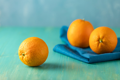 Three ripe juicy orange on wooden turquoise table surface. Close up, copy space for you text, shallow depth of the field.