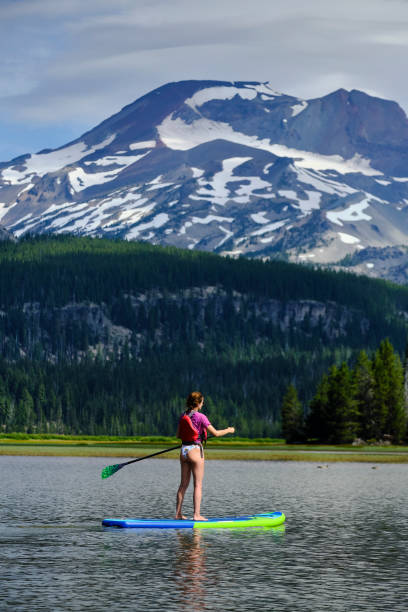 istock Young woman paddle boards across lake 1227003599