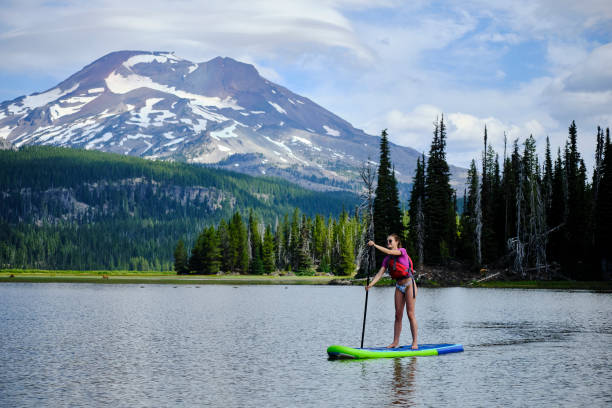 istock Young woman paddle boards across lake 1227003681