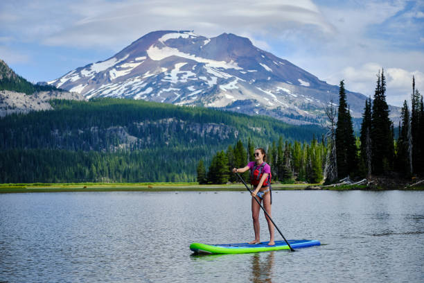istock Young woman paddle boards across lake 1227003684