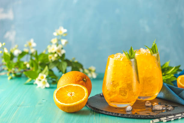 Two glass of orange ice drink with fresh mint on wooden turquoise table surface. Alcoholic non-alcoholic drink-beverage. stock photo