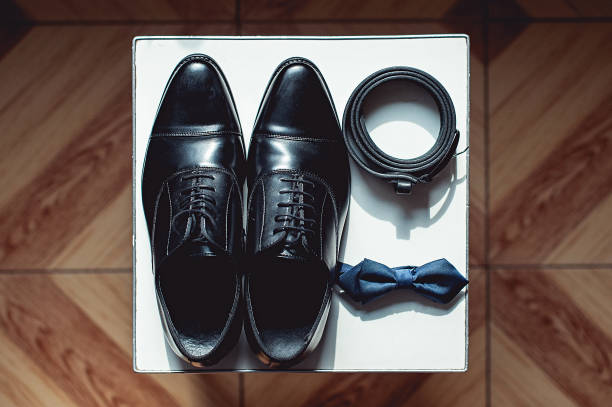 nahaufnahme von modernen mann zubehör. schwarze fliege, lederschuhe und gürtel. - shoe groom wood luxury stock-fotos und bilder