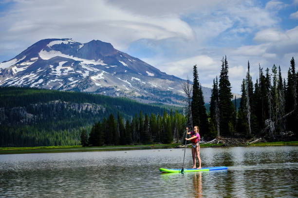 istock Young woman paddle boards across lake 1227004186