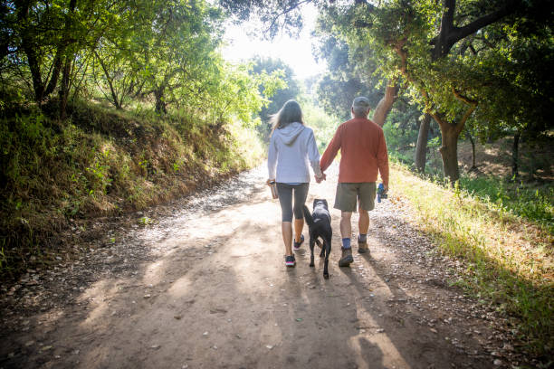 istock Active senior couple Walking with Dog on nature trail 1227004254