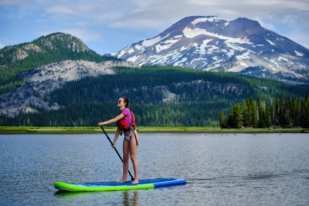 istock Young woman paddle boards across lake 1227004987