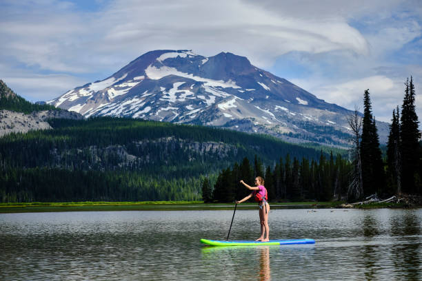 istock Young woman paddle boards across lake 1227004989
