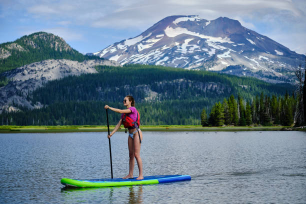 istock Young woman paddle boards across lake 1227005314