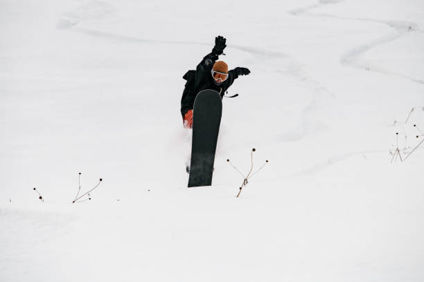 istock Snowboarder freerider balances when lands after fly on snowboard over snowy hillside 1227005520