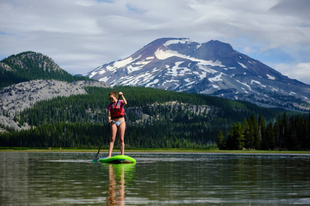 istock Young woman paddle boards across lake 1227007314