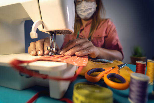 close up latin female hands sewing with sew machine homemade medical face mask for preventing and stop corona virus spreading - textile industry and covid19 healthcare concept - seam needle textile industry thread imagens e fotografias de stock