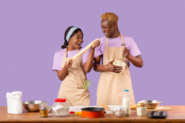 istock Young black family enjoying cooking process, spending weekend together on color background 1227008759