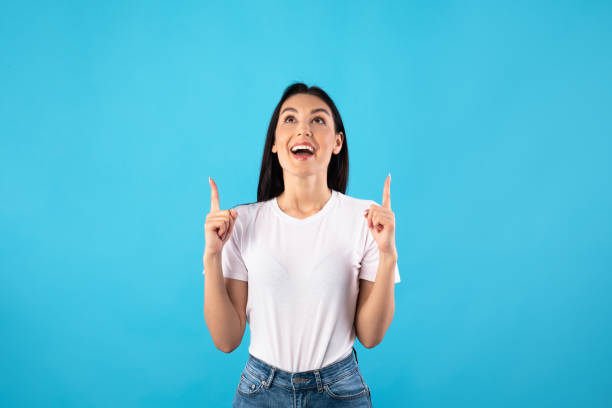 istock Smiling woman pointing fingers up at free space 1227009098