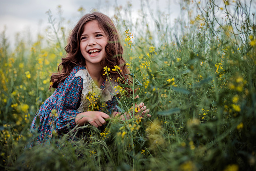 Cheerful young girl laughing when enjoying her day in nature, picking wild flowers