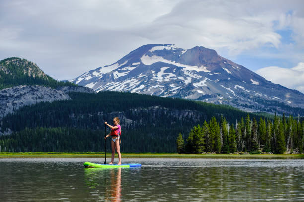 istock Young woman paddle boards across lake 1227009897