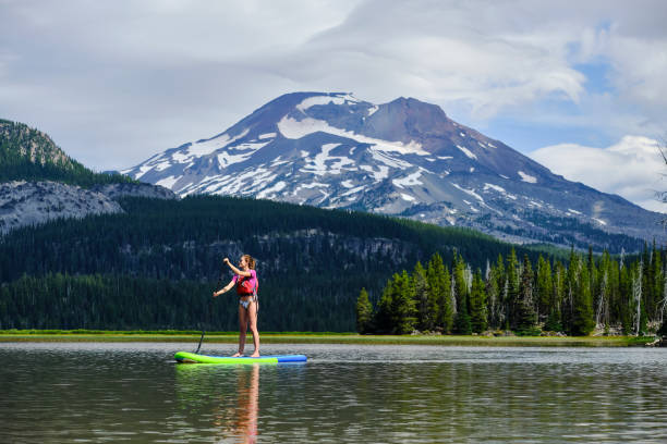 istock Young woman paddle boards across lake 1227009898
