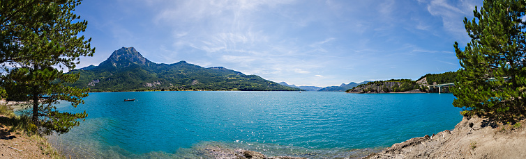 Panorama of Serre-Ponçon Lake with boat and mountains in the background