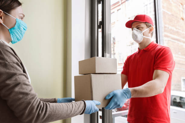 istock Contactless delivery at home. Courier passes boxes to client 1227009987