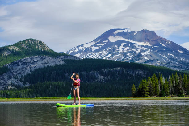 istock Young woman paddle boards across lake 1227010246