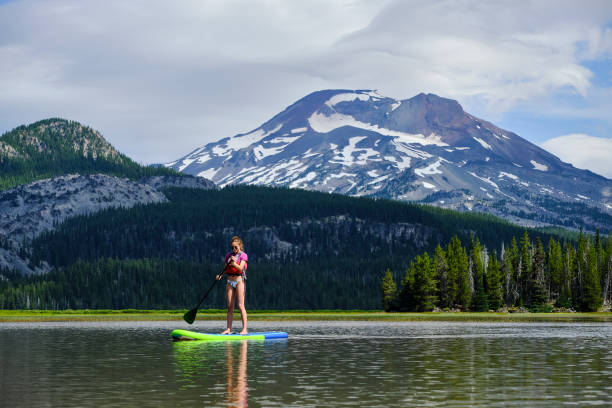 istock Young woman paddle boards across lake 1227011087