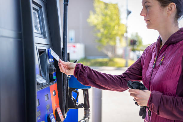 donna che paga alla pompa del carburante alla stazione di servizio con pagamento contactless - gas station foto e immagini stock