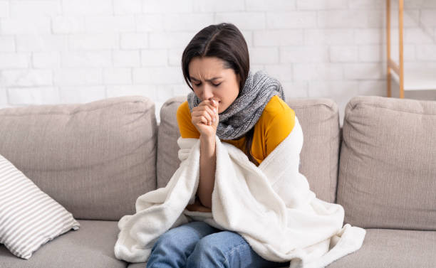 istock Sick young lady suffering from virus, coughing into her hand at home 1227011233