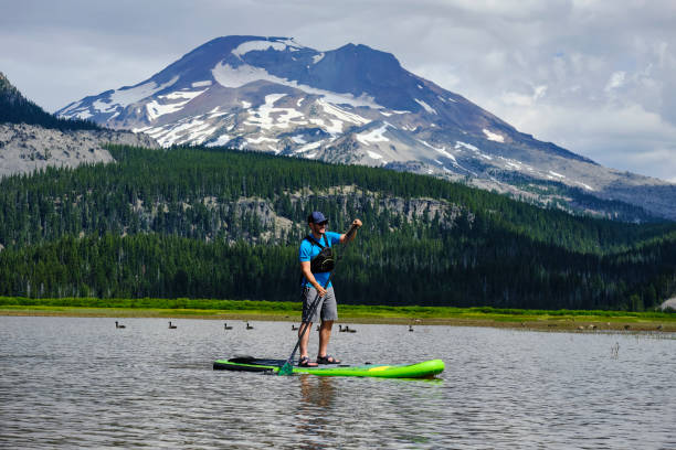 istock Young man paddle boards across lake 1227012532