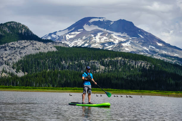 istock Young man paddle boards across lake 1227012533