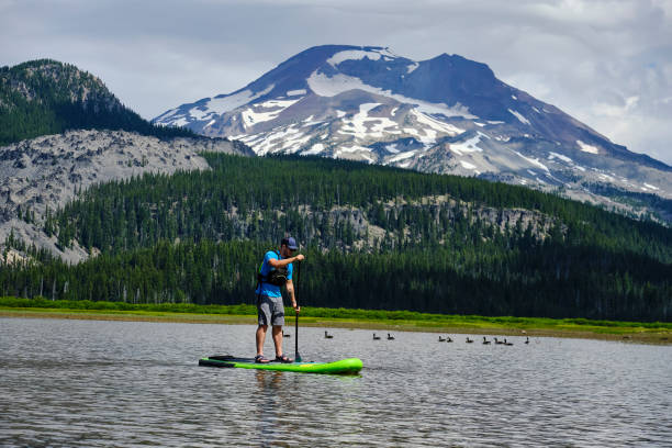 istock Young man paddle boards across lake 1227012534