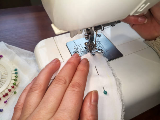 istock Woman stitches a white cloth on a sewing machine 1227012613