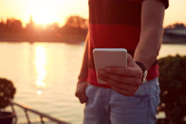 istock Man holding cellphone near river. 1227013088