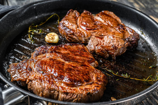 istock Cooked grilled marble steak Chuck roll in a pan. Dark background. Top view 1227013164