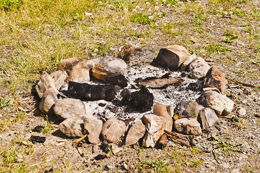 A burnt-out campfire ring surrounded by stones.
